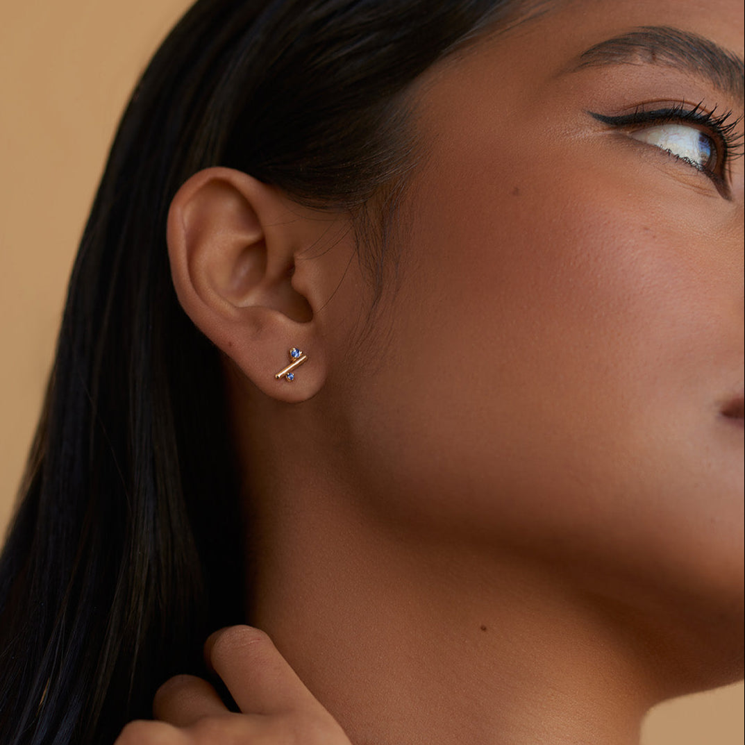 Gold earrings with blue gemstones on a white background